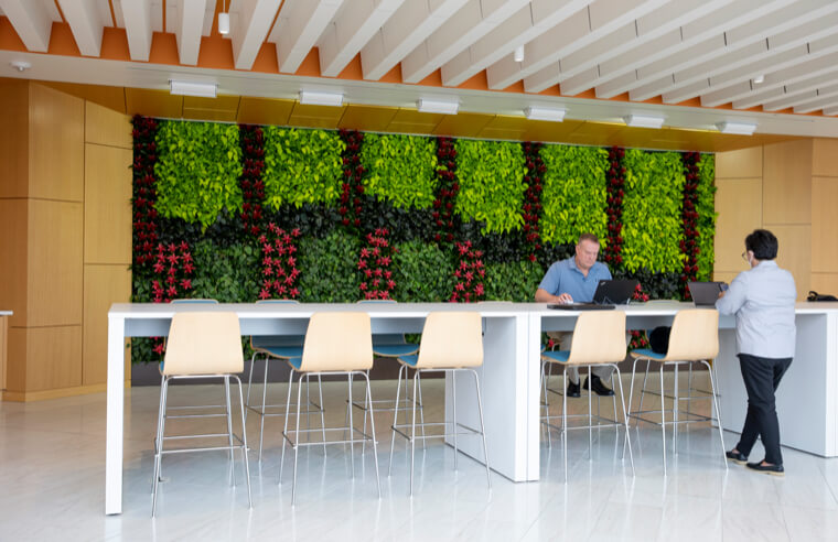 Image of two people working on their laptops at a long, high table